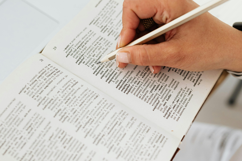 Learner using a pencil with an open dictionary to build vocabulary