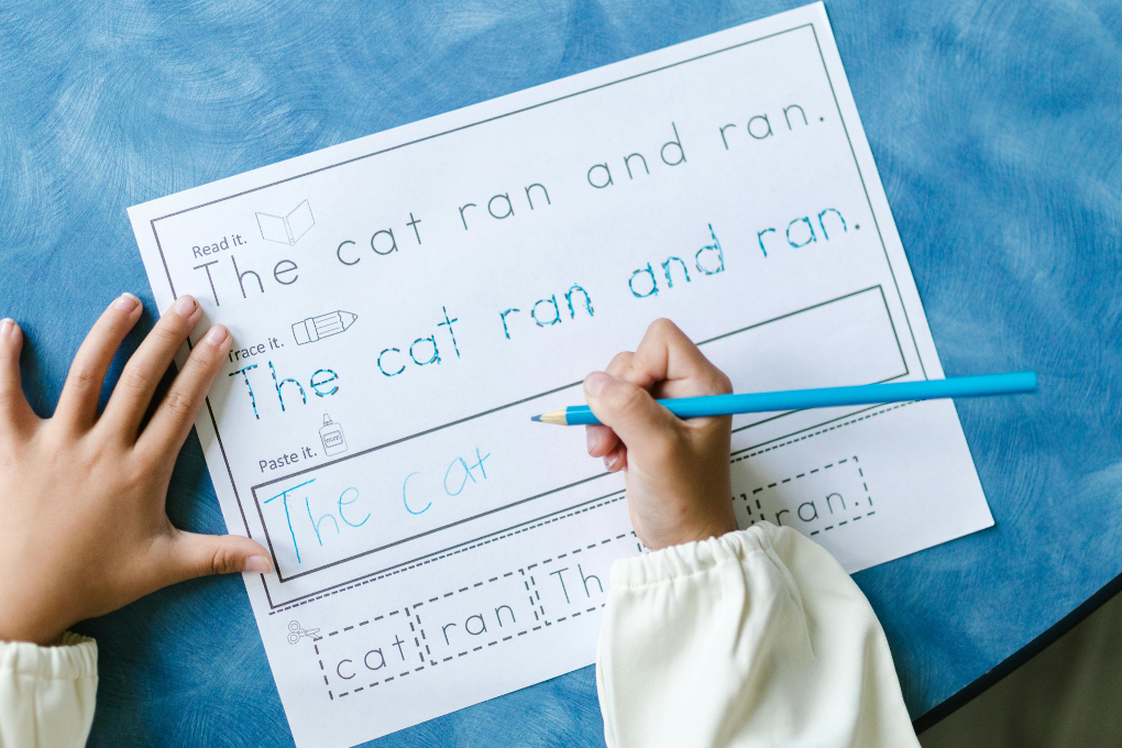 Child completing a Grade R literacy worksheet tracing "The cat ran and ran"