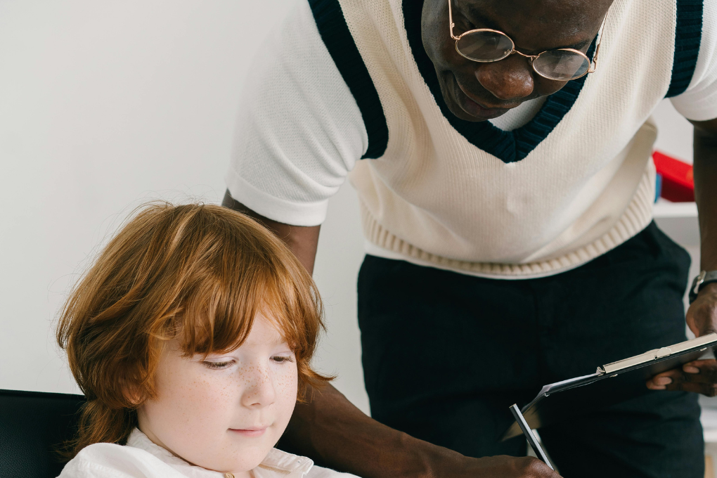 Teacher assisting a young learner with a tablet in hand