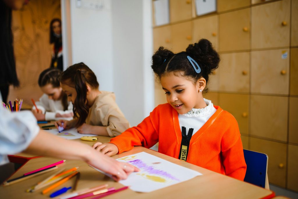Young learner completing a worksheet with teacher support — highlights classroom engagement and reinforces the value of CAPS-aligned printables available on grade.co.za for early grades.