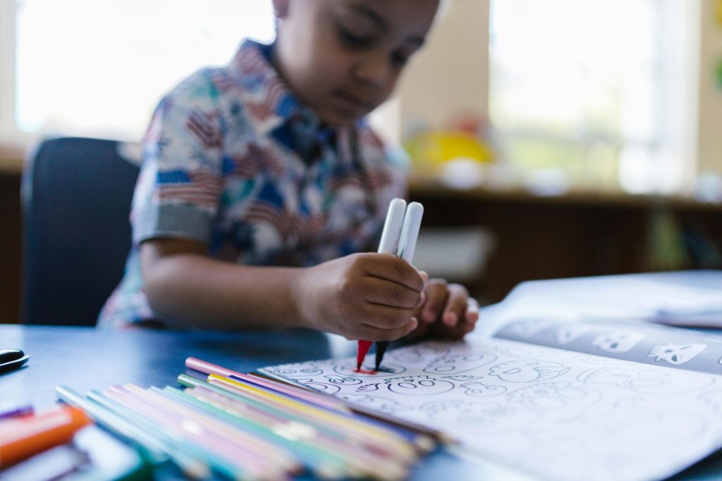 A young child filling in large, simple shapes on a digital coloring page.